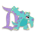 Sulley with one claw raised beside a lavender glitter Signature D